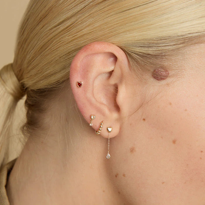 Woman wearing solid gold daith earrings stacked with other solid gold piercing jewellery on her right ear.