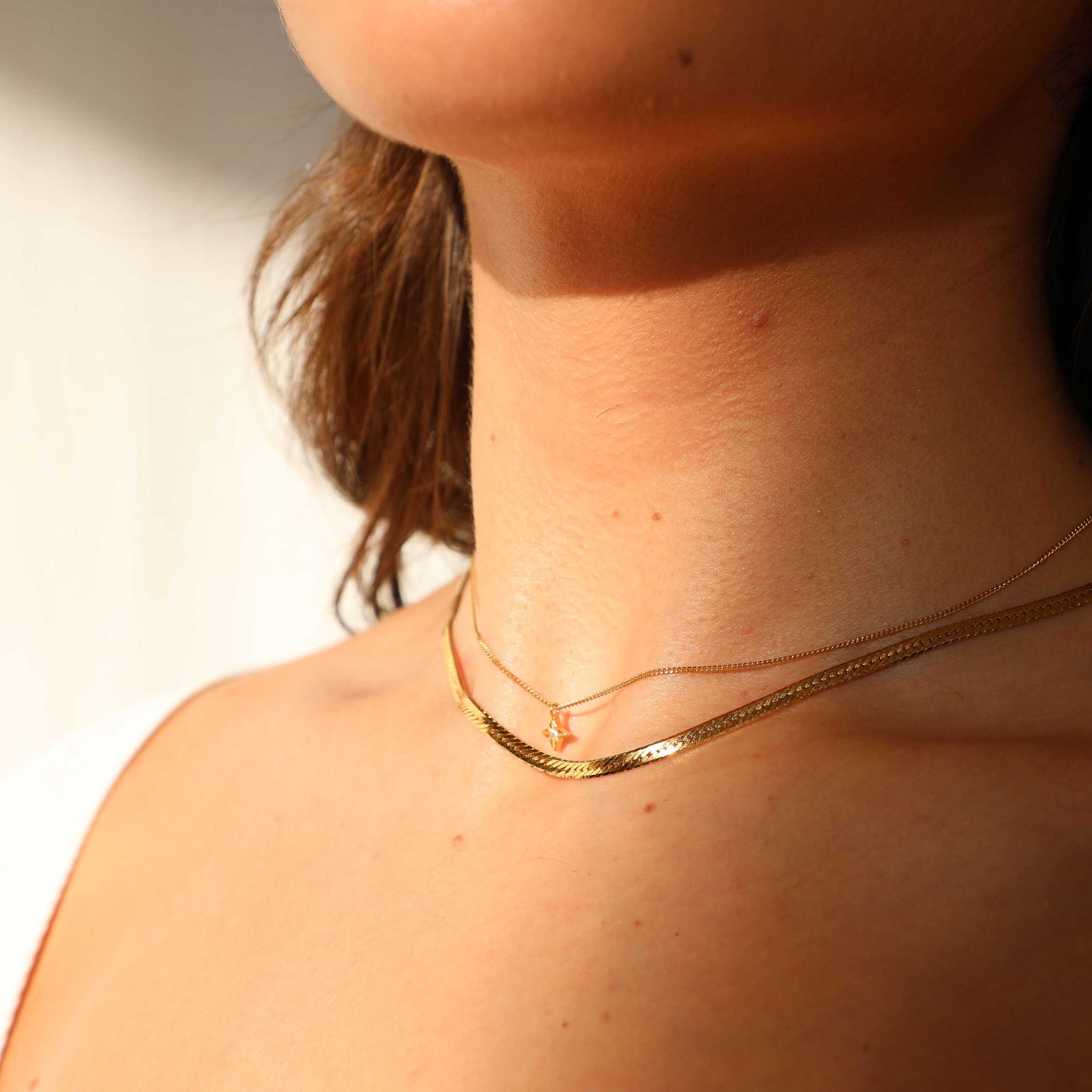 Gold snake chain worn with dainty pendant necklace