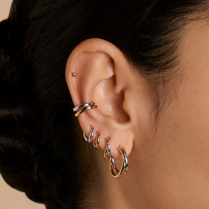 Side profile of a woman wearing matching Astrid & Miyu crystal huggies and ear cuffs in gold.