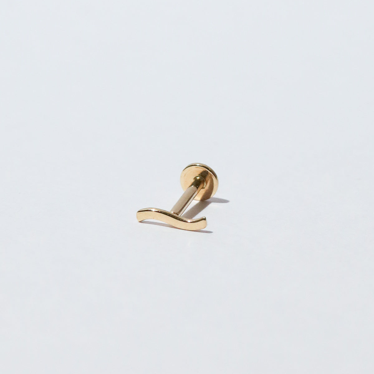 Wave Piercing Stud in Solid Gold flat lay