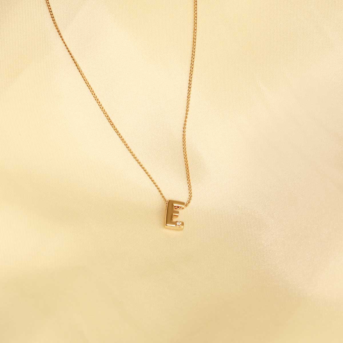 Flat lay shot of E Initial Pendant Necklace in Gold