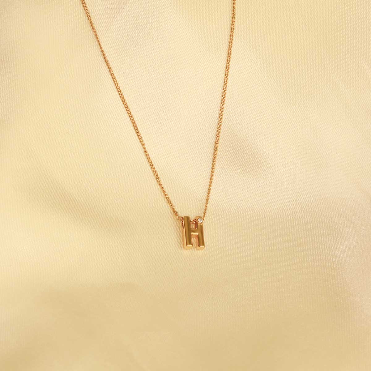 Flat lay shot of H Initial Pendant Necklace in Gold