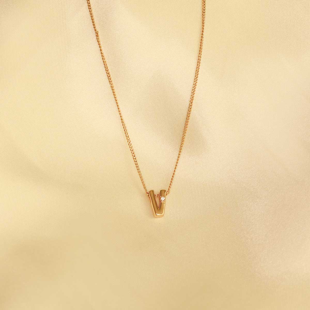Flat lay shot of V Initial Pendant Necklace in Gold