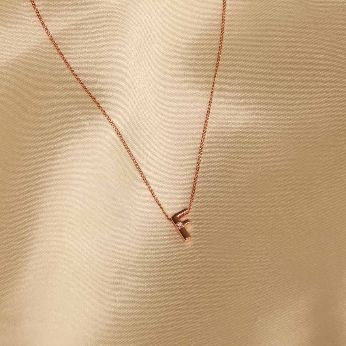 Flat lay shot of F Initial Pendant Necklace in Rose Gold