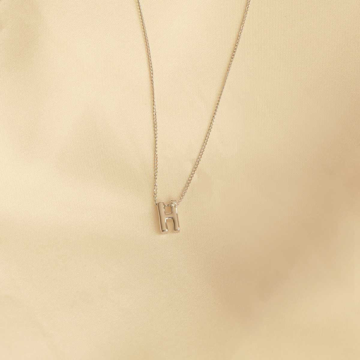 Flat lay shot of H Initial Pendant Necklace in Silver