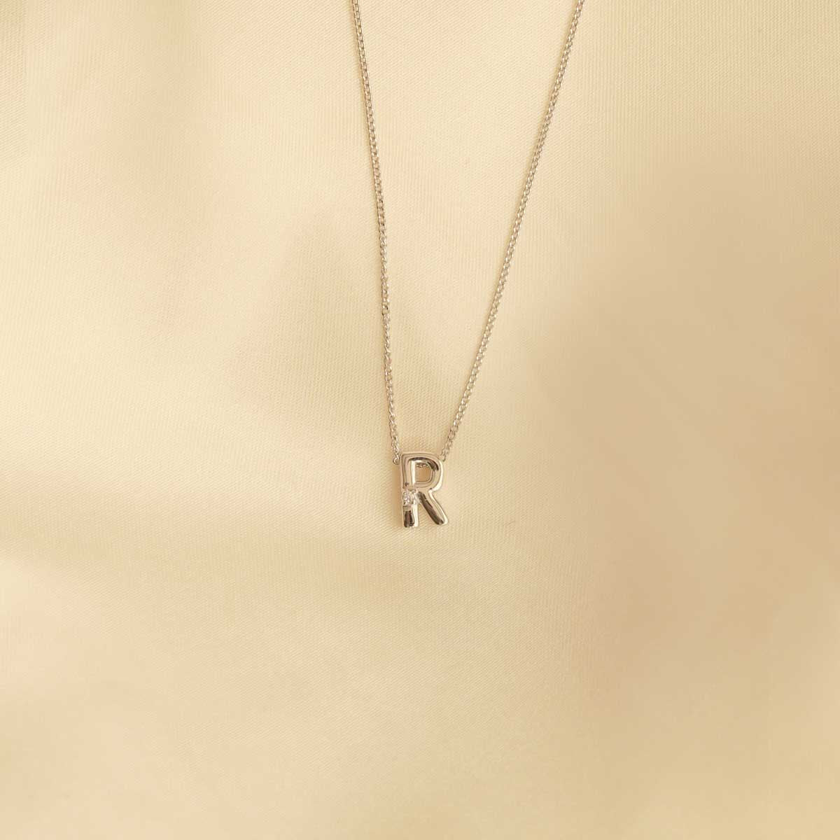 Flat lay shot of R Initial Pendant Necklace in Silver