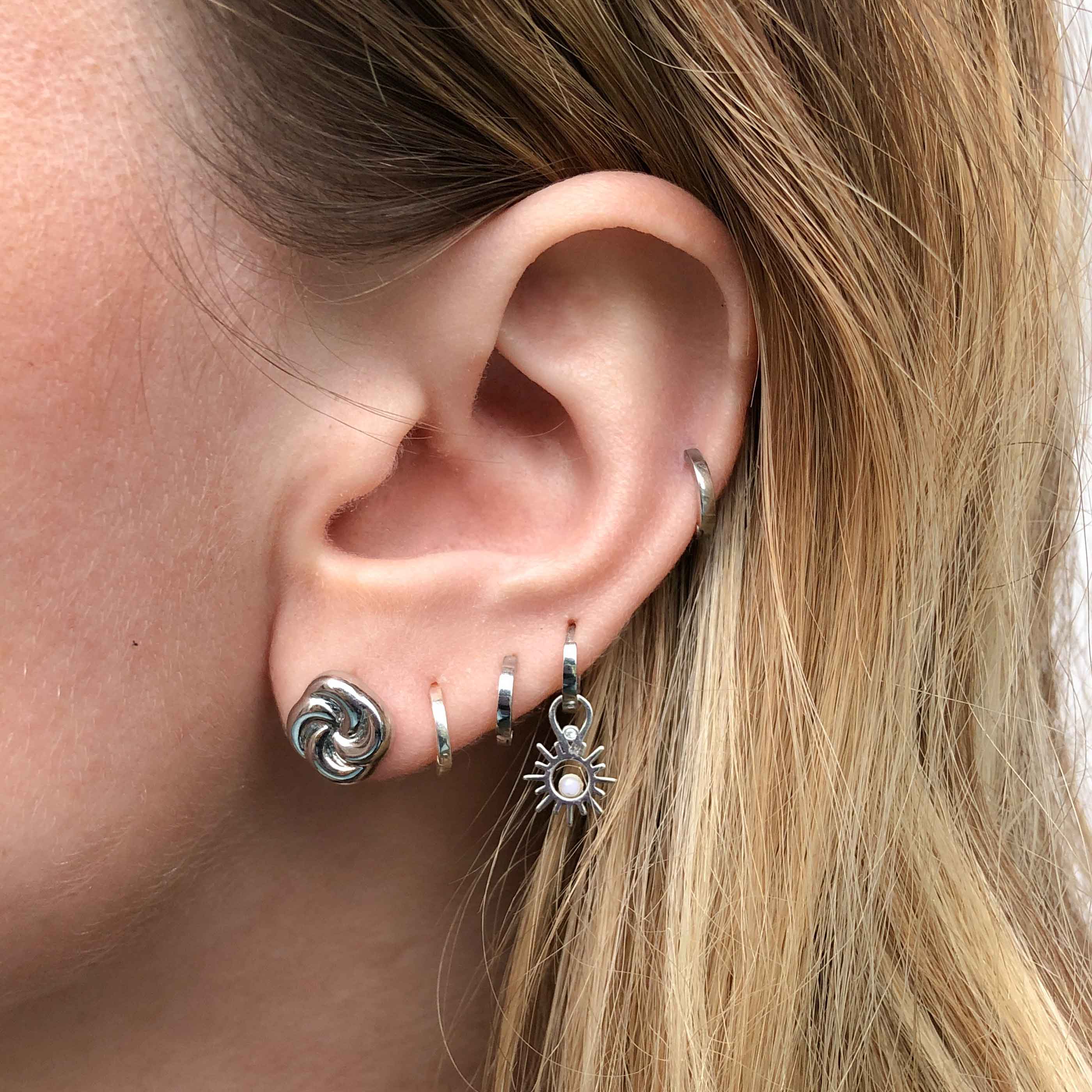 Knot Stud Earrings in Silver worn with silver huggie earrings